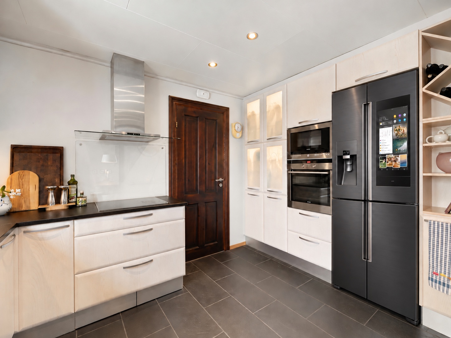 Black touchscreen refrigerator and built-in appliances in a bright kitchen